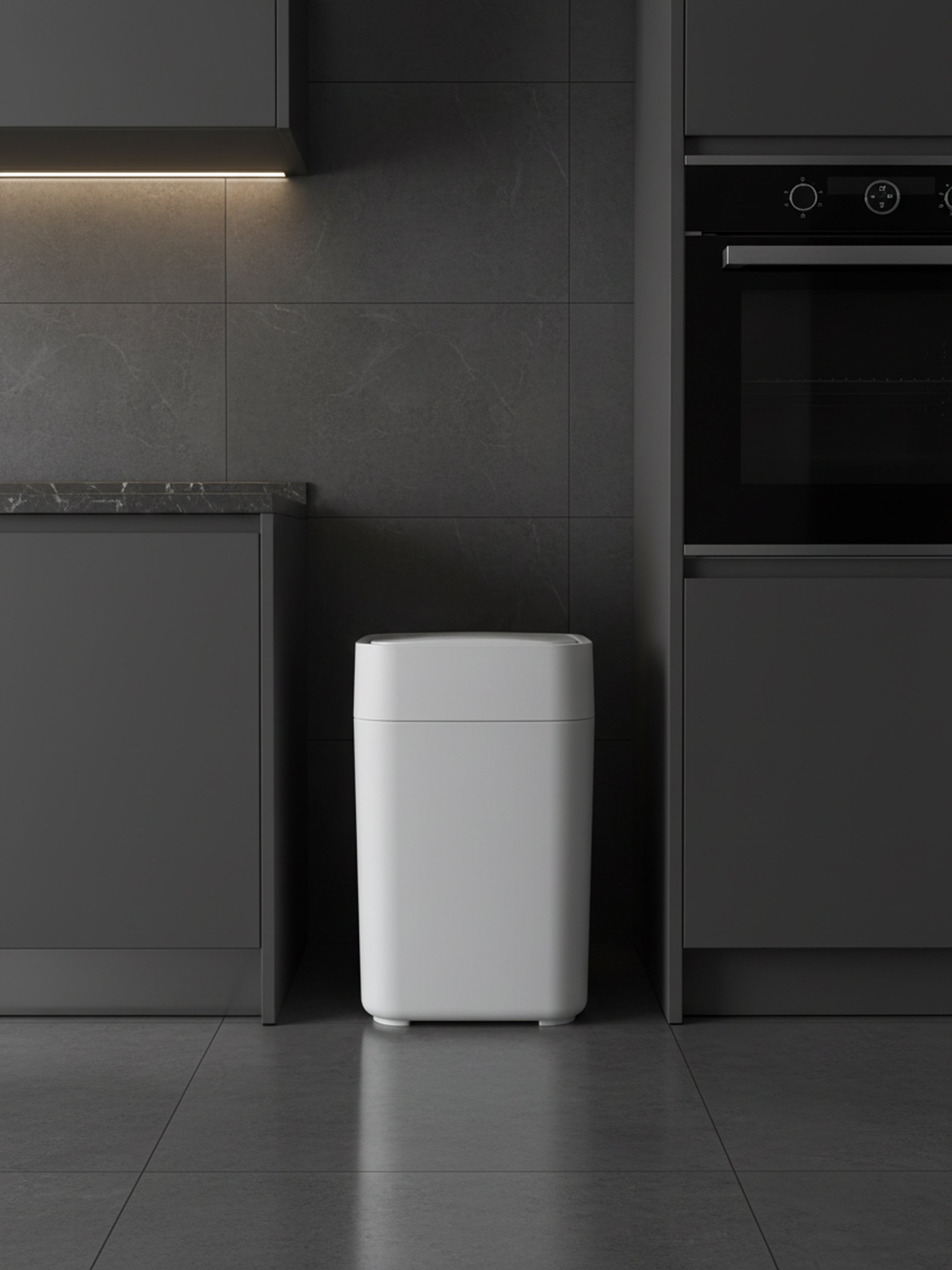 White trash bin in a modern kitchen setting with dark cabinets and tiles.